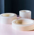 Three cylindrical vanilla bowls of various heights and widths are placed on a pink and blue gradient background