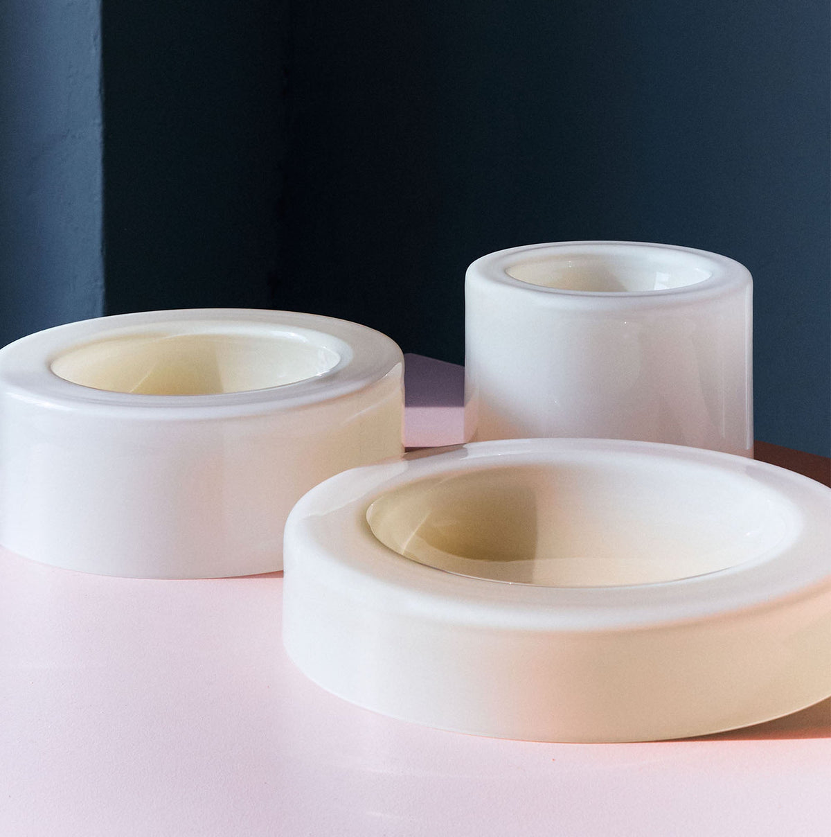 Three cylindrical vanilla bowls of various heights and widths are placed on a pink and blue gradient background