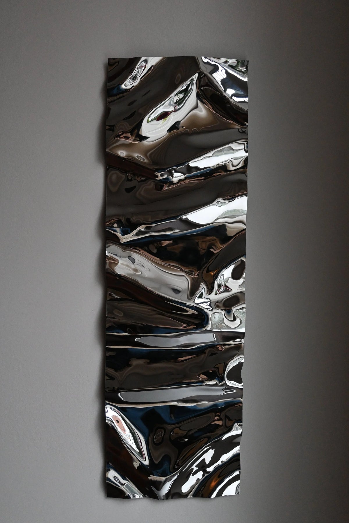Psychedelic Mirror 30*100 cm — hand-shaped polished steel, angle view showing craftsmanship