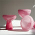 Set of pink plastic chairs on a white surface with a neutral background