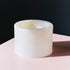A high vanilla bowl placed at the corner of a soft pink table against a dark wall in the background.