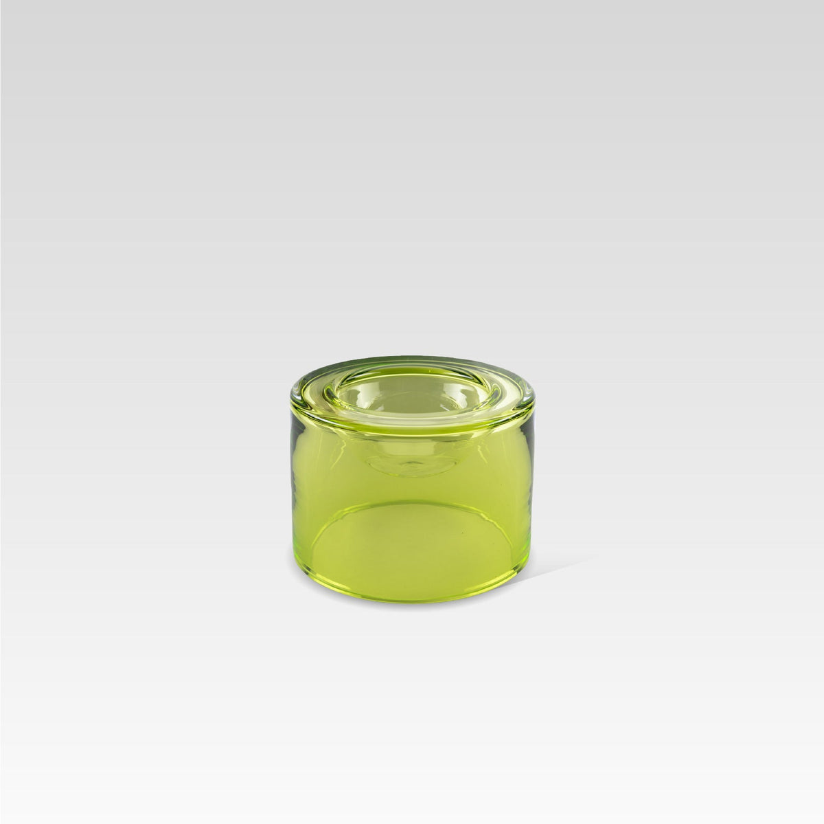 A high-green lime color glass wet bowl, positioned on a grey background. 